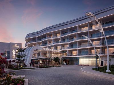 Moderní hotel s zakřivenou fasádou a osvětleným vstupem za soumraku