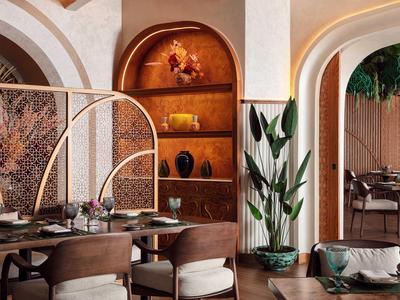 Elegantní hotelová restaurace s zakřivenými oblouky, dřevěným nábytkem a teplými tóny.