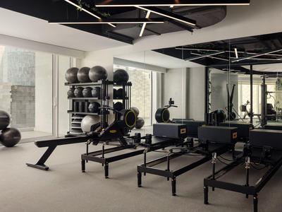 Moderner Fitnessraum mit Pilates-Geräten und großen Fenstern.