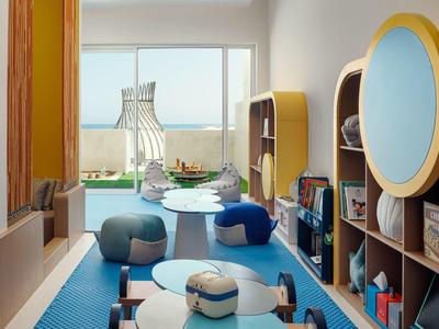 Moderní dětský herní koutek s barevnými sedacími pytli, stoly a regály v světlé místnosti.