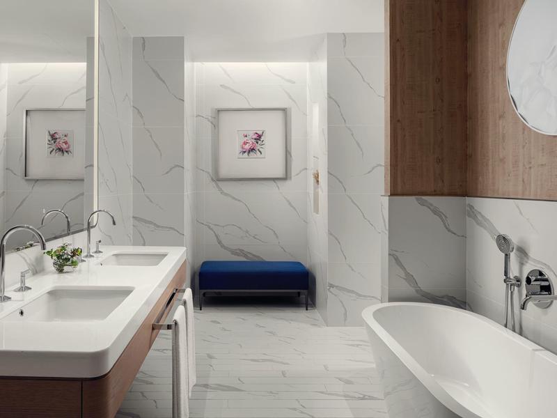 Moderní koupelna s volně stojící vanou, dvojnásobným umyvadlem a mramorovými stěnami