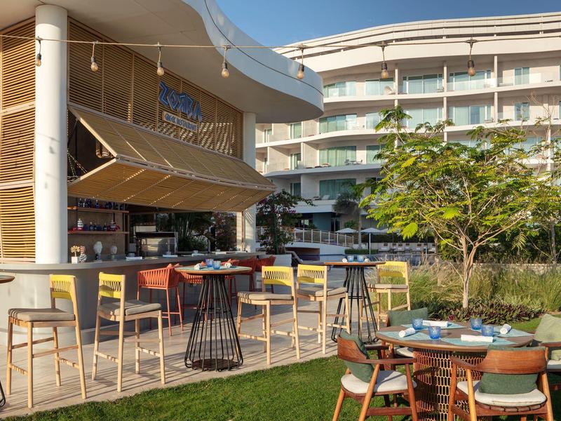 Moderní venkovní prostor hotelu s barem a posezením za denního světla.