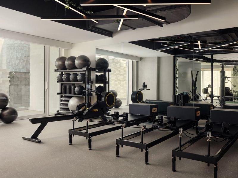 Moderní fitness místnost s pilates vybavením a velkými okny v hotelu.