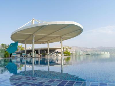 Großer Pool mit rundem, weißem Sonnendach und klarer Spiegelung bei klarem Himmel.