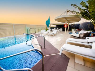 Bazén s lehátky a výhledem na moře při západu slunce.