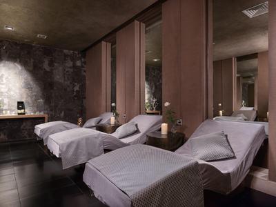 Dunkler Wellnessraum mit drei weißen Liegen, warmem Licht und entspannender Atmosphäre.