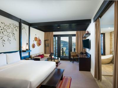 Modern hotel room with large bed and mountain view.