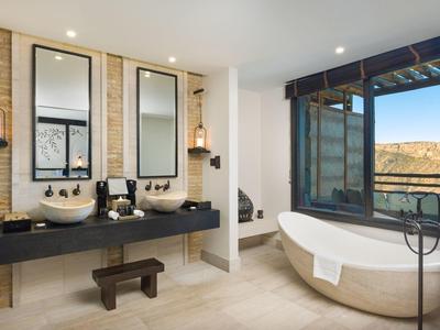 Modern bathroom with two sinks, freestanding bathtub, and large window with a view.