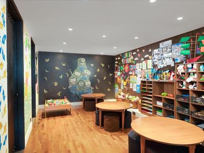Interior with wooden floor, round tables, and colorful decorative posters on the walls.