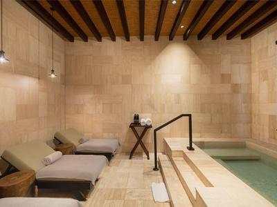 Relaxation area with loungers and small pool, illuminated by warm lights.