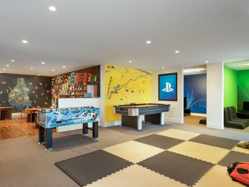 Modern game room with foosball, air hockey, and colorful lounge areas.