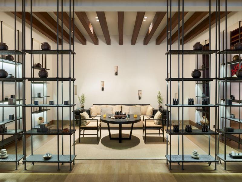 Modern lounge area with shelving walls, wooden beam ceiling, and cozy seating furniture.
