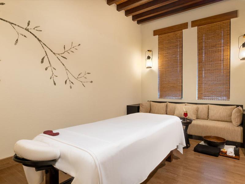Calm massage room with wooden beam ceiling, comfortable table, and cozy seating area.