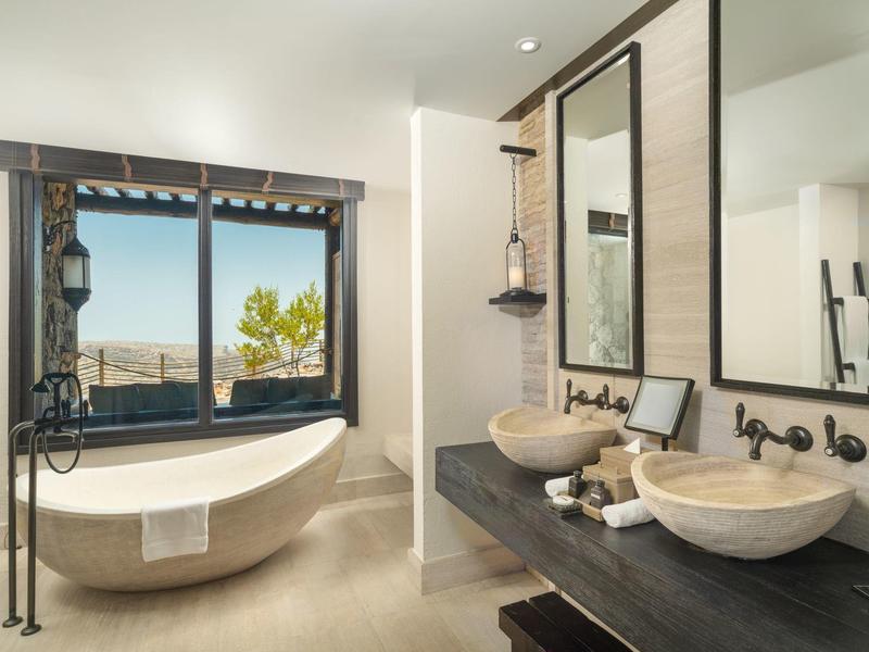 Bright bathroom with freestanding bathtub and double sinks in front of large mirrors.