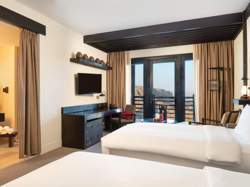 Modern hotel room with double beds, TV, and bathroom with shower.