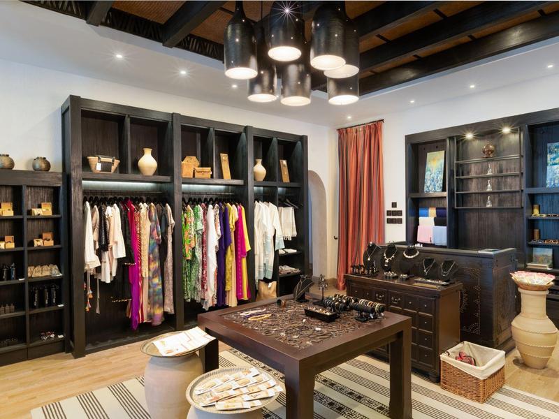 Interior of a stylish shop with clothing and ceramics on shelves and tables.