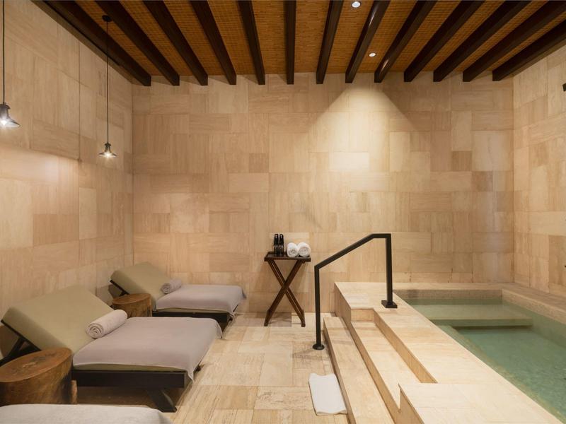 Relaxation area with loungers and small pool, illuminated by warm lights.