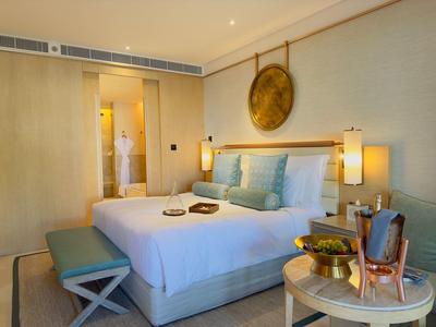 Gezellige hotelkamer met groot bed, bankje, nachtkastjes en moderne verlichting.