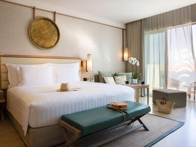 Lichte hotelkamer met kingsize bed, bank, zithoek en balkon met uitzicht op bergen.