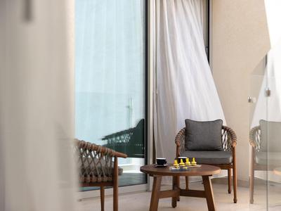 Balkon met houten stoelen, een kleine tafel en uitzicht op zee door glazen deuren.