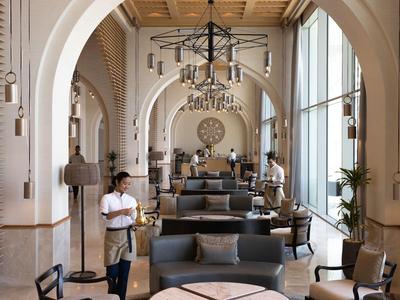 Elegante area lounge dell'hotel con archi alti, ampie finestre e posti a sedere confortevoli.