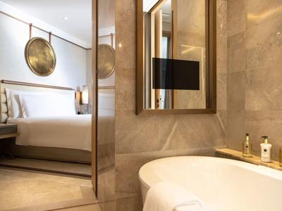 Elegant hotelkamer met badkuip, spiegel en moderne slaapkamer met tweepersoonsbed.