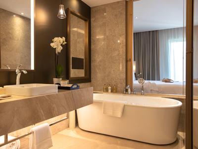 Modern hotelbadkamer met vrijstaand bad, wastafel en elegante spiegel.