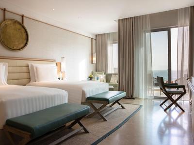 Moderne hotelkamer met twee bedden, banken en een balkon met uitzicht op de oceaan.