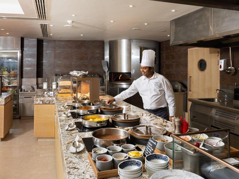 Chef bereidt eten in een moderne hotelkeuken met diverse gerechten en ingrediënten op het aanrecht.