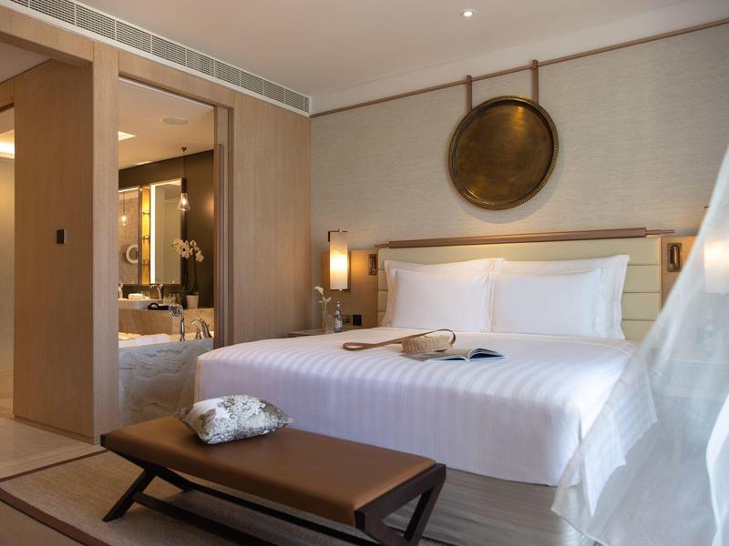 Modern hotelkamer met groot bed, houten meubels en decoratief wandobject.