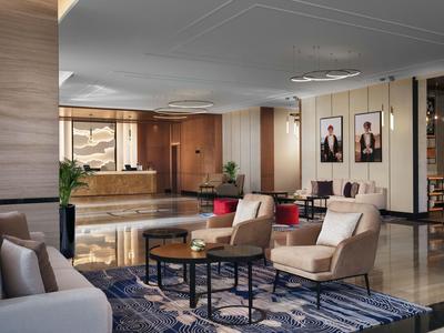 Nowoczesny hol hotelowy z wygodnymi fotelami, sofami i recepcją w tle.