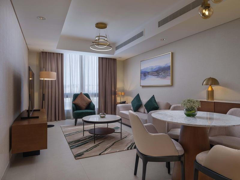 Modern living room with sofa, coffee table, and dining area with chairs.