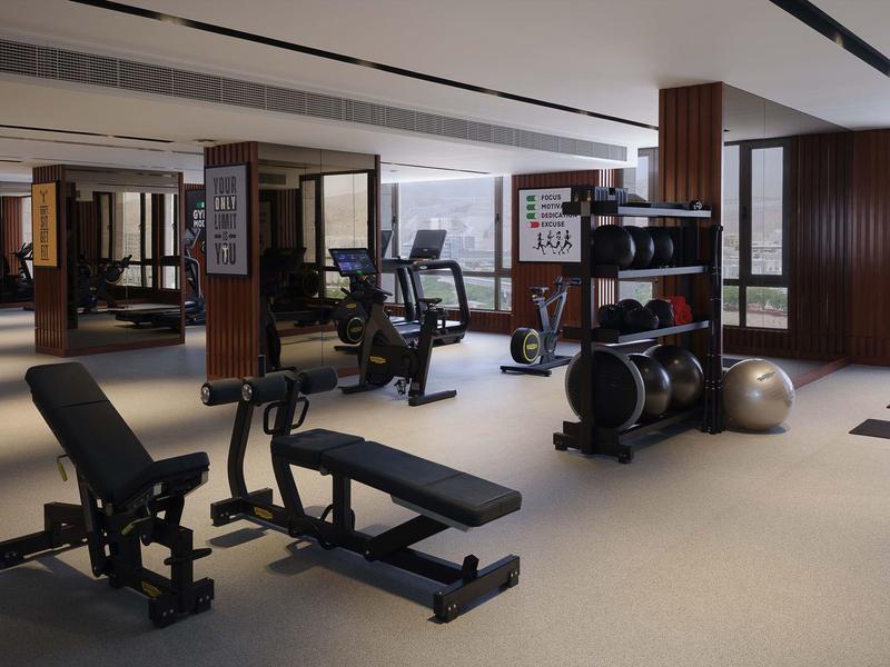 Modern gym with various exercise equipment and large windows.