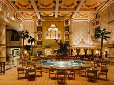 Amplio interior con fuente central, estatuas y áreas de descanso en hotel con iluminación cálida.