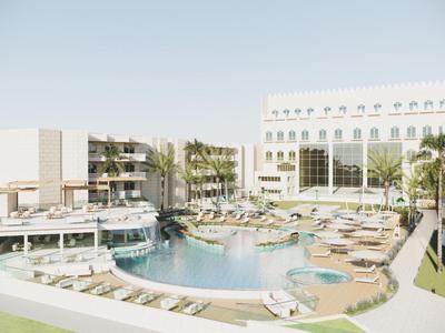 Hotel de lujo con gran piscina, tumbonas y palmeras verdes bajo un cielo despejado.