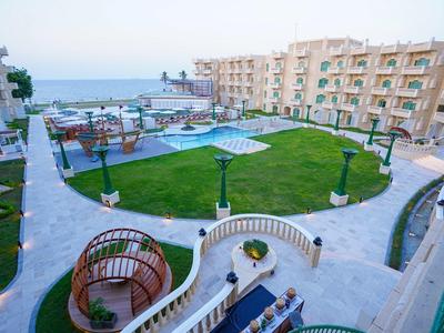 Vista de un complejo hotelero con varios edificios, un jardín central y piscinas cerca del mar.