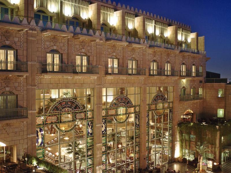 Edificio de hotel iluminado con grandes ventanas y terraza de noche en ambiente urbano.
