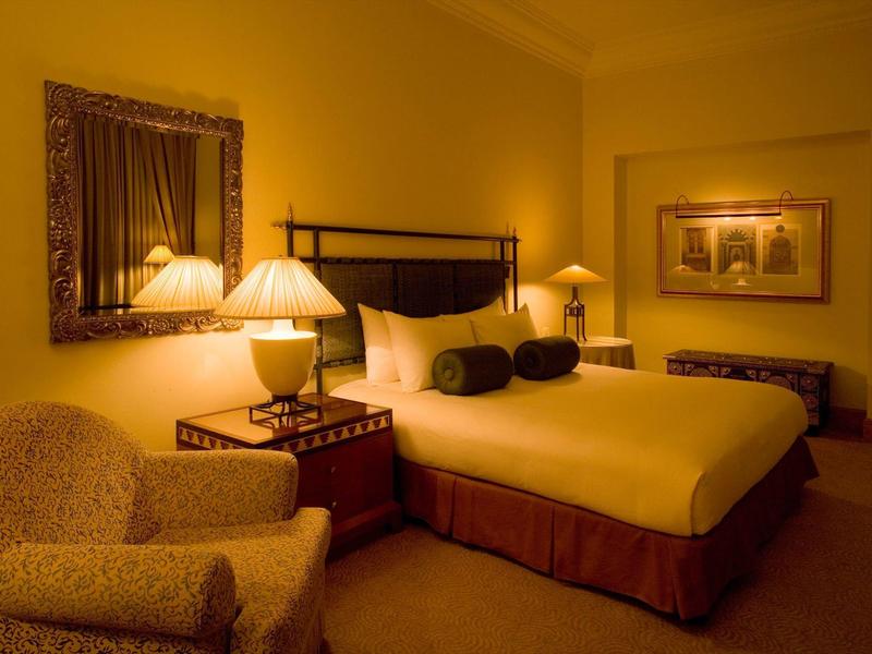 Habitación de hotel acogedora con cama grande, sillón y luz cálida de lámparas.