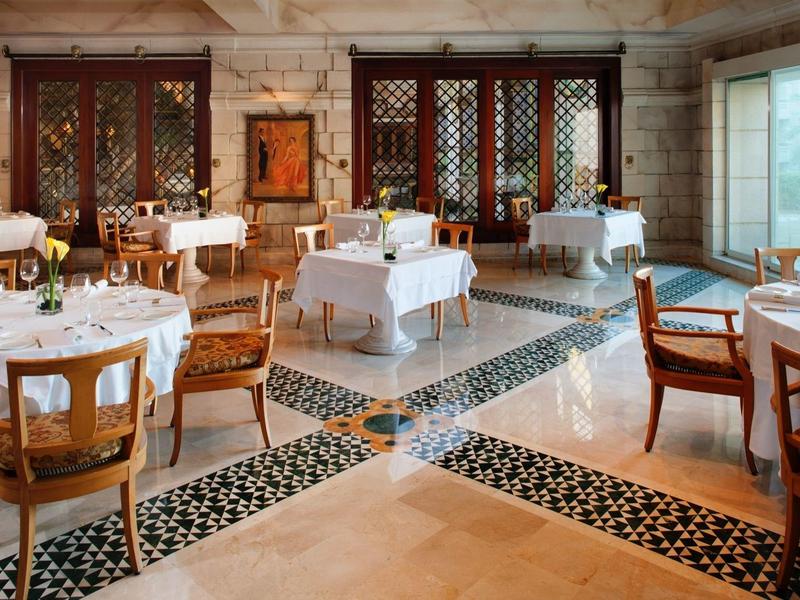 Restaurante elegante con muebles de madera, manteles blancos y gran ventana con vista al exterior.