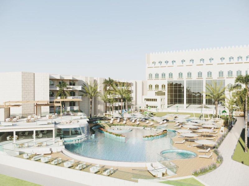 Hotel de lujo con gran piscina, tumbonas y palmeras verdes bajo un cielo despejado.