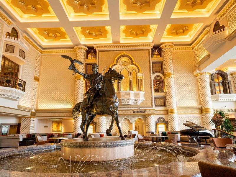 Lujoso vestíbulo de hotel con estatua de jinete en el centro y techo iluminado y artístico.