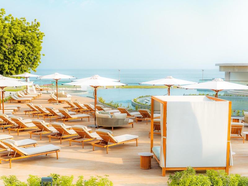 Terraza soleada con tumbonas y sombrillas junto al mar, ideal para relajarse en el hotel.