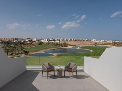 Blick von einer Terrasse auf einen Golfplatz mit Teichen und Wohnungen im Hintergrund.