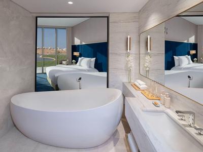 Modernes Badezimmer mit freistehender Badewanne und Spiegelwand in neutralen Farbtönen.