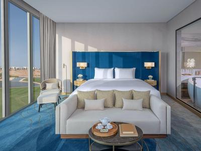 Modernes Hotelzimmer mit Sofa, großem Bett und Panoramafenstern mit Blick auf die Stadt.