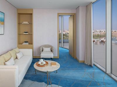 Modernes Hotelzimmer mit Sofa, Sesseln, blauem Teppich und großen Fenstern mit Flussblick.