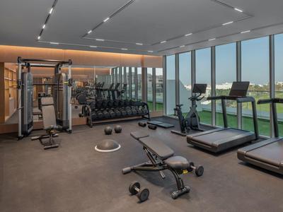 Moderner Fitnessraum mit Laufbändern und Hanteln, großer Fensterfront mit Blick ins Freie