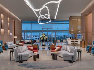 Moderne Hotellobby mit Sitzgruppen, eleganten Leuchten und großer Fensterfront mit Blick nach draußen.