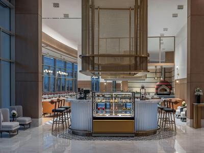 Moderner Barbereich in einem Hotel mit runden Tresen, Barhockern und hellem Marmorboden.