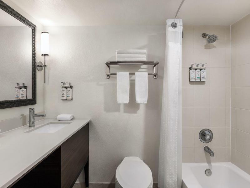 Jasna, nowoczesna łazienka z umywalką, toaletą, ręcznikami i wanną z zasłoną prysznicową.